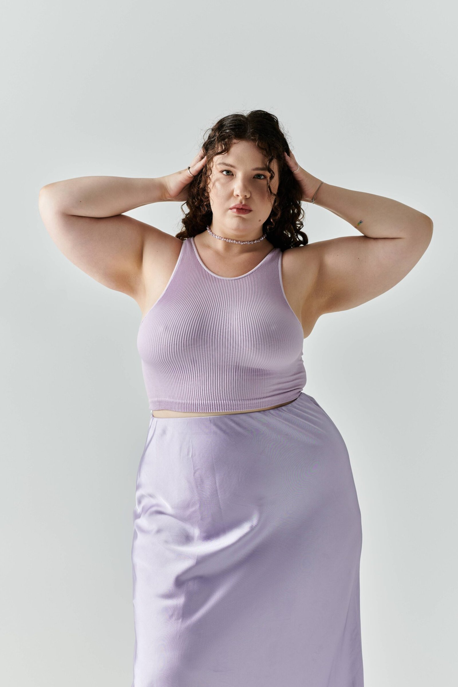 elegant-plus-size-woman-poses-confidently-lavender-outfit-against-soft-backdrop